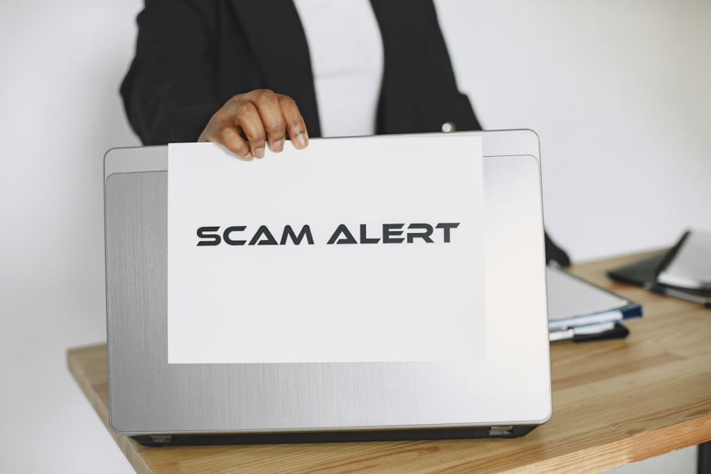  “Scam Alert” written on a paper, stuck to a laptop