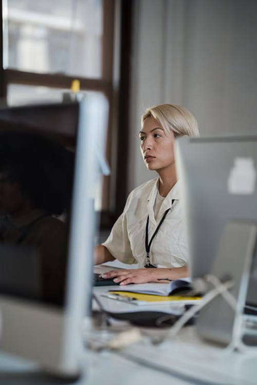 A healthcare professional with a lanyard working at a desktop computer in an office setting