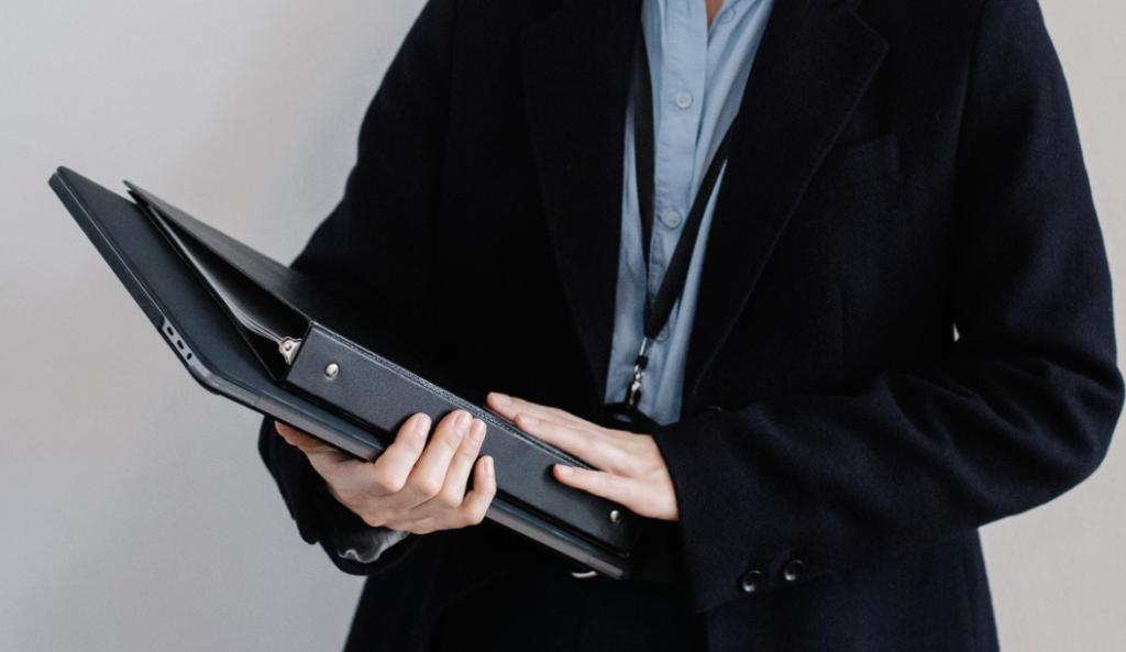 This photo shows a person holding paper folders inside an office.