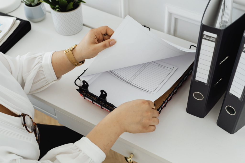 This photo shows a woman organizing office files in a binder.