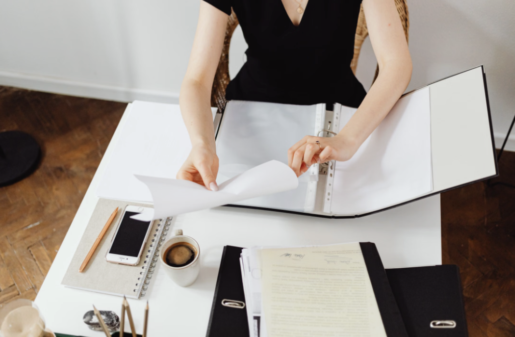 This photo shows a woman organizing paper documents into a file folder.