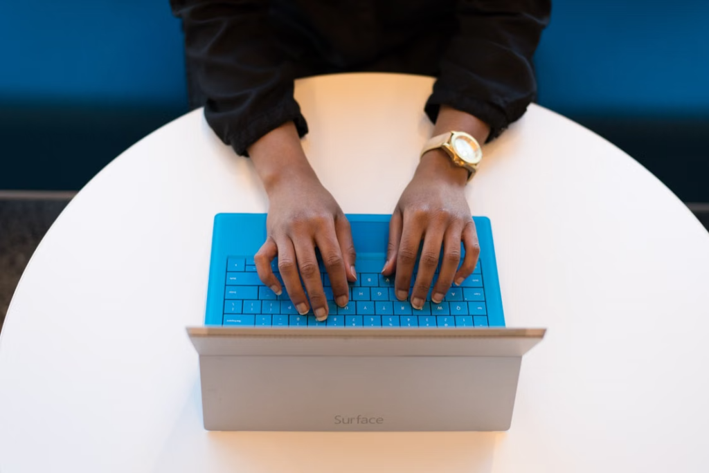 A person typing on a laptop keyboard.