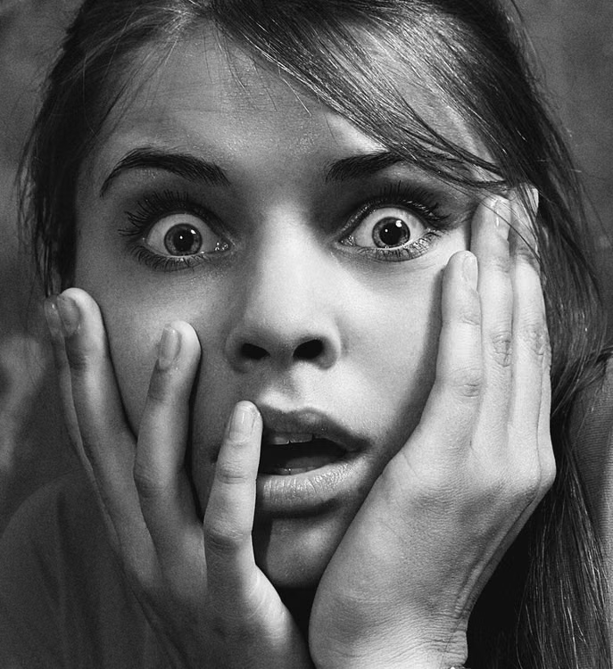 A close-up black-and-white photo of a shocked woman's expression.